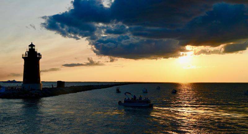 The sun prepares to drop out of a cloud bank near sunset June 14 on Delaware Bay with the Delaware Breakwater East End Lighthouse in the foreground. Freedom Boat Club and Cape Water Tours joined forces during a sunset cruise.