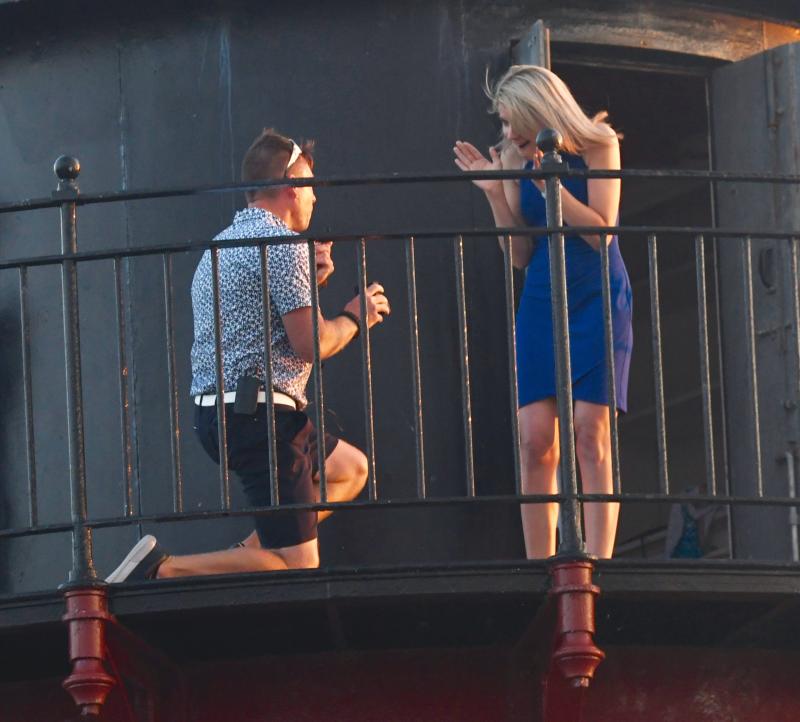 Down on one knee, Lee Vandeloecht proposes to a surprised Megan Elizabeth Bailey as he pops the question on the walkway of the East End Lighthouse.