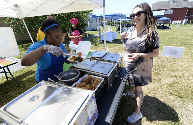 Membership Director Shay Almond, right, gets some Caribbean Cuisine of fried fish, mac & cheese and greens from Tolete Reid.